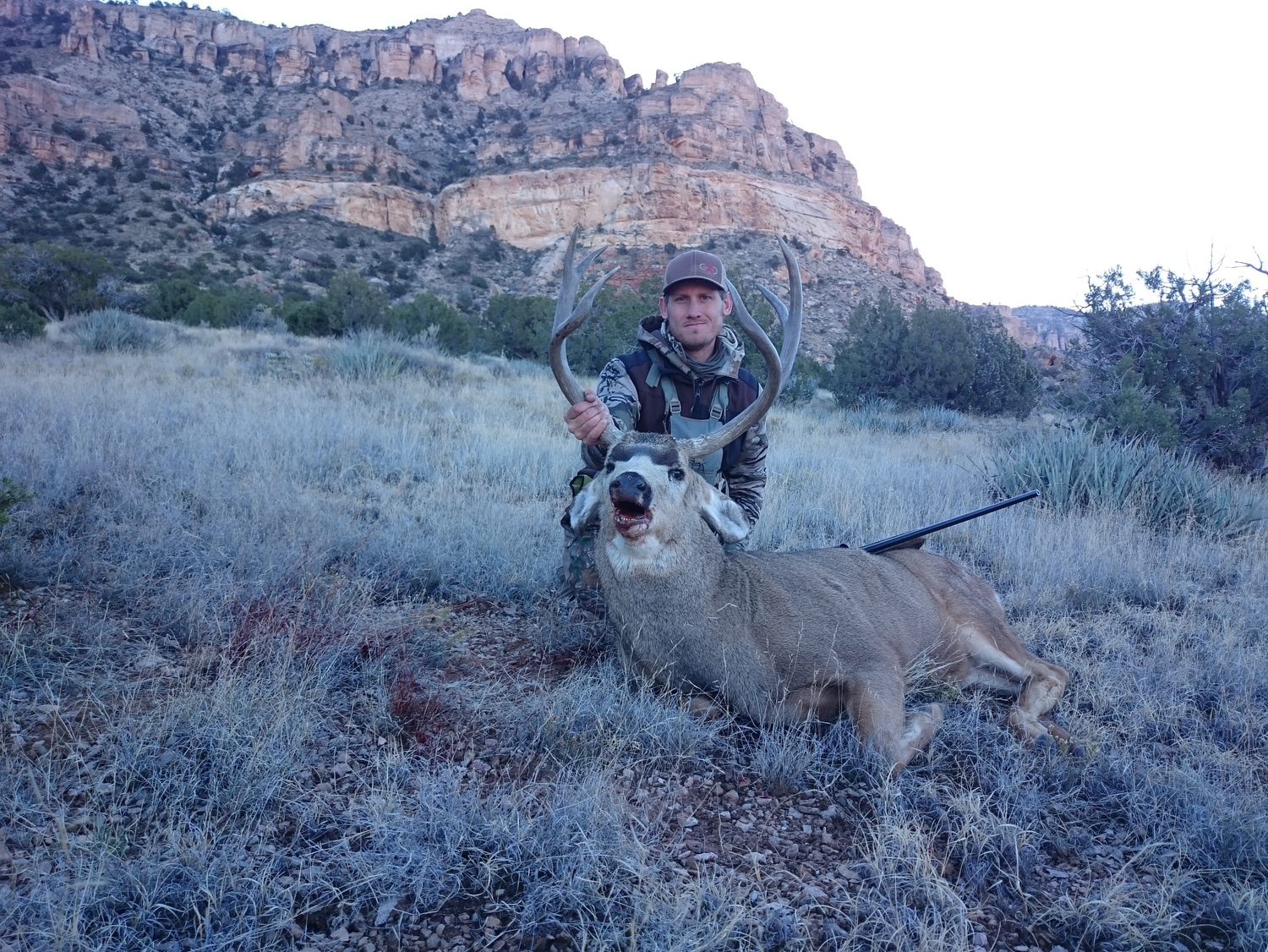 Christopher kneeling with a mule deer buck