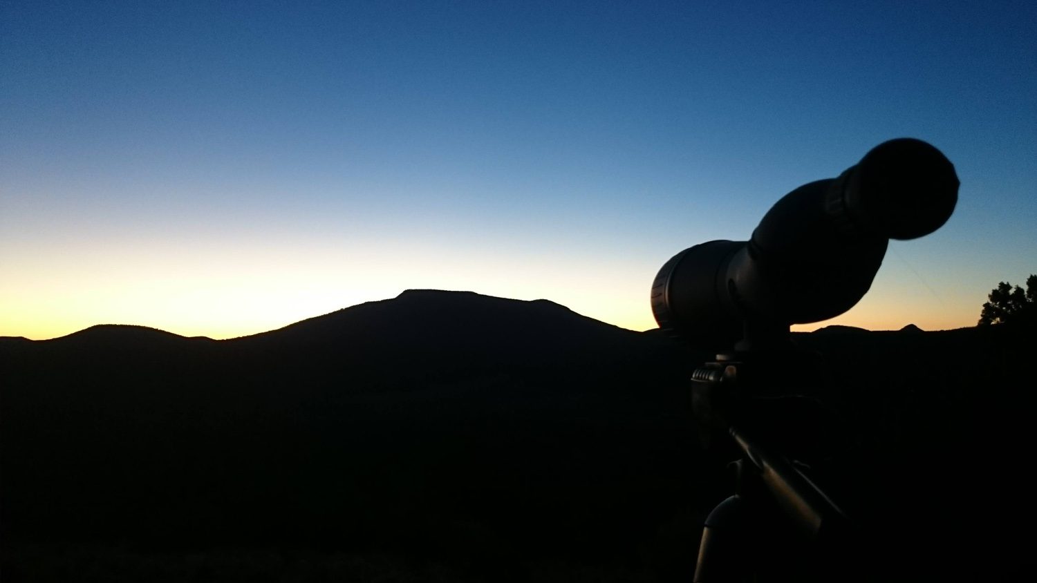 Spotting scope silhouetted against a sunrise sky